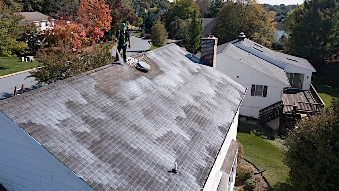 technician spraying roof rejuvenation treatment on asphalt shingle roof